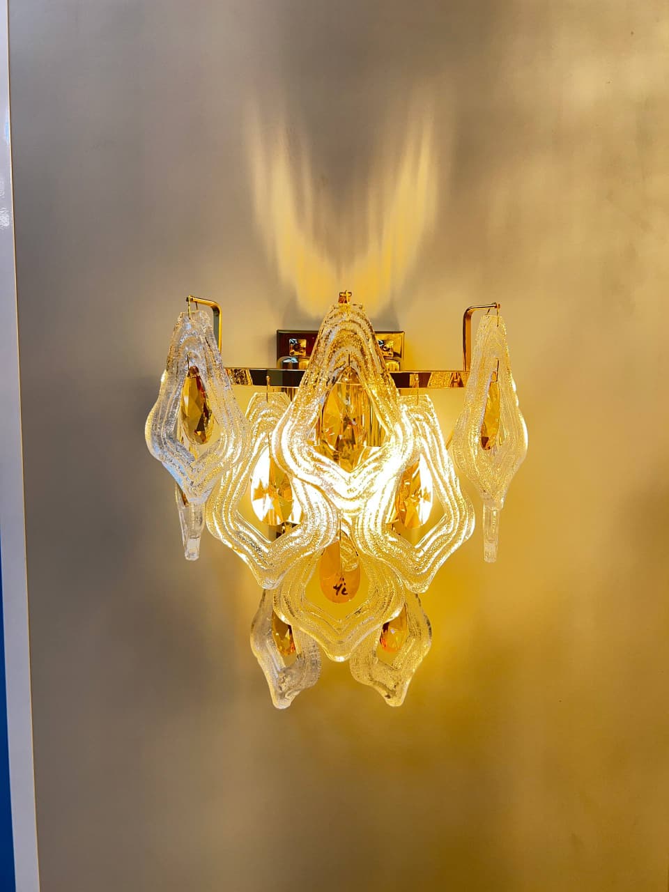 Arandela de parede Lysan com cristais, acabamento dourado, acesa, ideal para cabeceira de cama e corredor, tamanho 27cm.